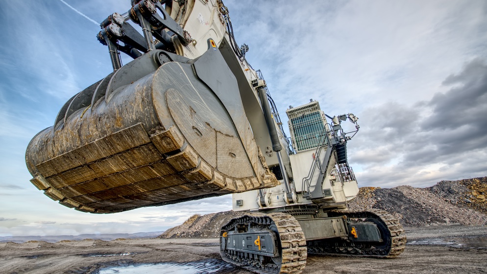Big excavator in coal mine at cloudy day, low angle view